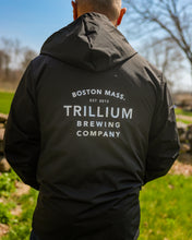 Load image into Gallery viewer, Male wearing unisex black water resistant jacket with white Trillium flower logo

