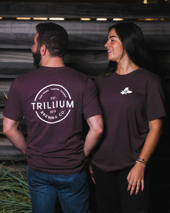 Male and Woman wearing maroon Trillium flower logo t-shirt