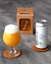 Load image into Gallery viewer, Leather coaster set with Trillium circle and flower logo in cardboard case tied with string. Beer can and clear glass
