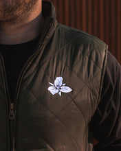 Load image into Gallery viewer, Male wearing men&#39;s olive quilted vest with white Trillium flower embroidery

